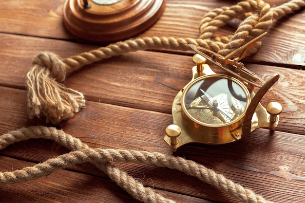 Compass and rope on wooden table close up
