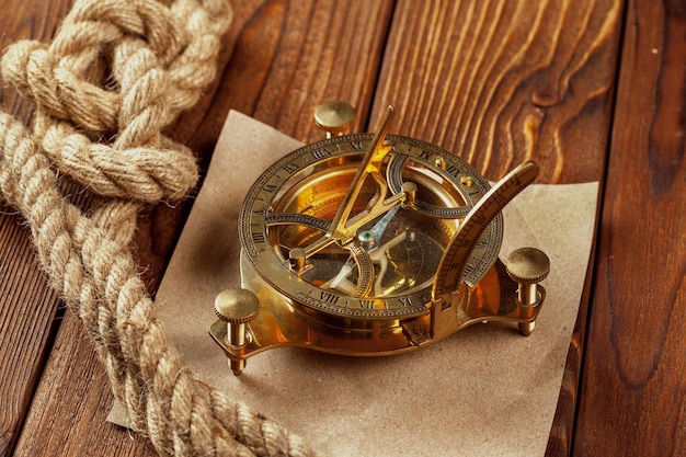 Compass and rope on wooden table close up