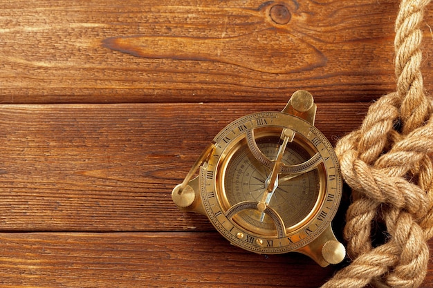 Compass and rope on wooden table close up