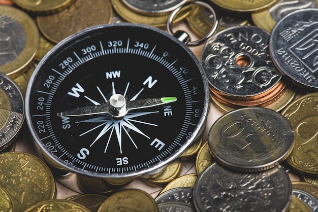 Free photo compass surrounded by coins