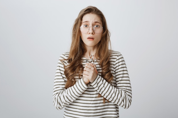 Compassionate and worried girl in glasses looking nervous