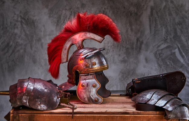 Complete combat equipment of the ancient Greek warrior lie on a box of wooden boards. Isolated on a dark background.