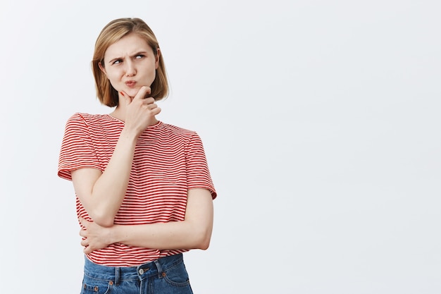 Complicated thinking blond girl looking upper right corner thoughtful, making choice