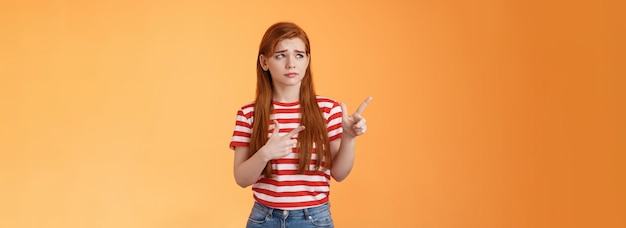 Foto gratuita complicata giovane ragazza dai capelli rossi carina e turbata perplessa di fronte a una decisione difficile e difficile sembra a disagio