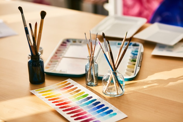 Composition on the artist's workplace, glasses with paint brushes and swatches
