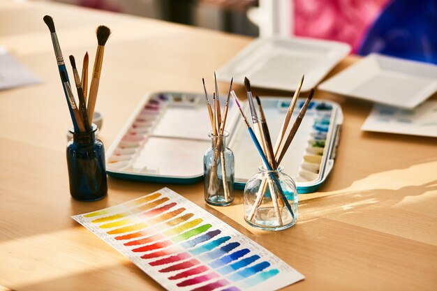 Composition on the artist's workplace, glasses with paint brushes and swatches