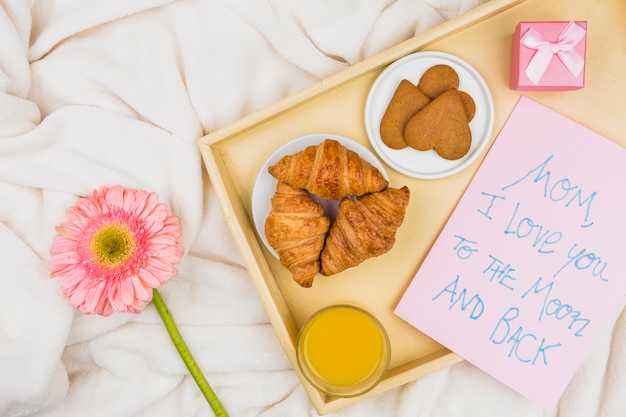 Free photo composition of bakery, glass and paper with words on tray near flower