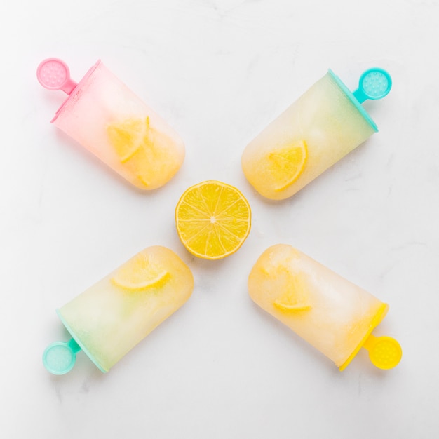 Free photo composition of cut lemon and ice popsicle with citrus on colorful sticks