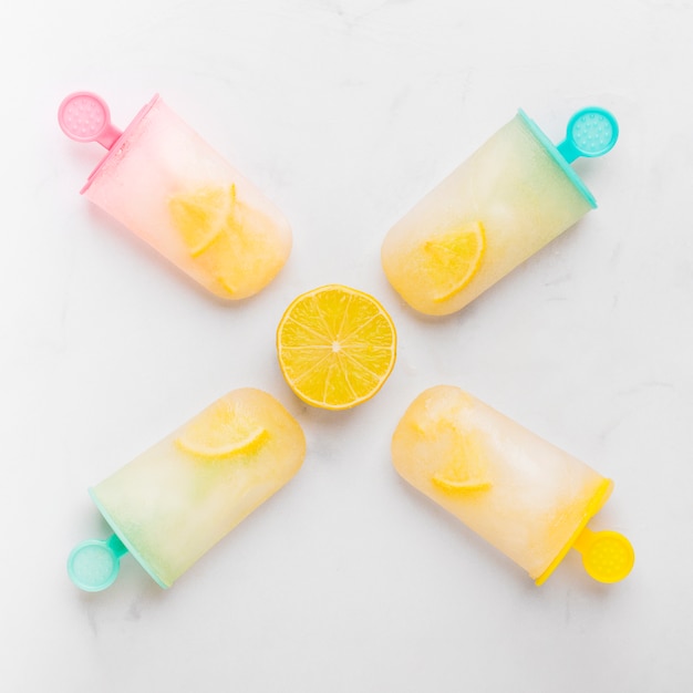 Composition of cut lemon and ice popsicle with citrus on colorful sticks