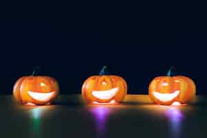 Бесплатное фото Композиция для хэллоуина с тремя подсвеченными тыквами