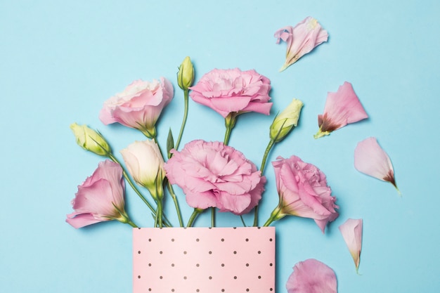 Free photo composition of fresh beautiful pink flowers in paper pack near petals