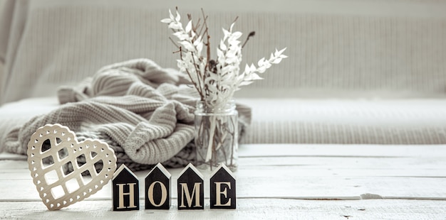 Composition in hygge style with the wooden word home, decor details and a knitted element