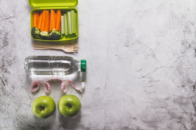 Foto gratuita composizione della scatola di pranzo con il cibo sano, bottiglia d'acqua e mele