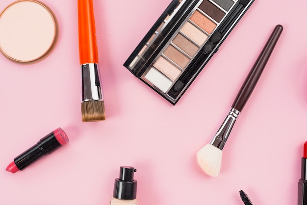 Composition of makeup and cosmetic beauty products laying on pink background 