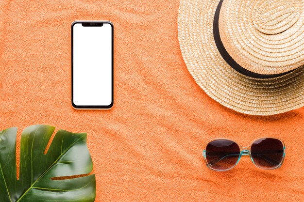 Композиция мобильного телефона шляпа солнцезащитные очки и листья растений