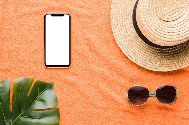 Composition of mobile phone hat sunglasses and plant leaf