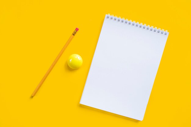 Composition of notebook pencil and yellow magnet