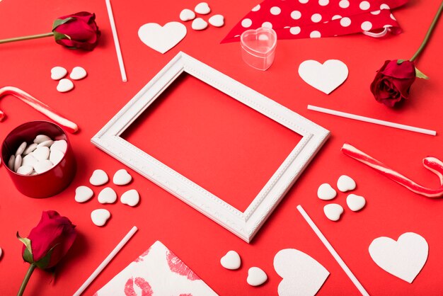 Composition of photo frame between paper hearts, flowers and wands 