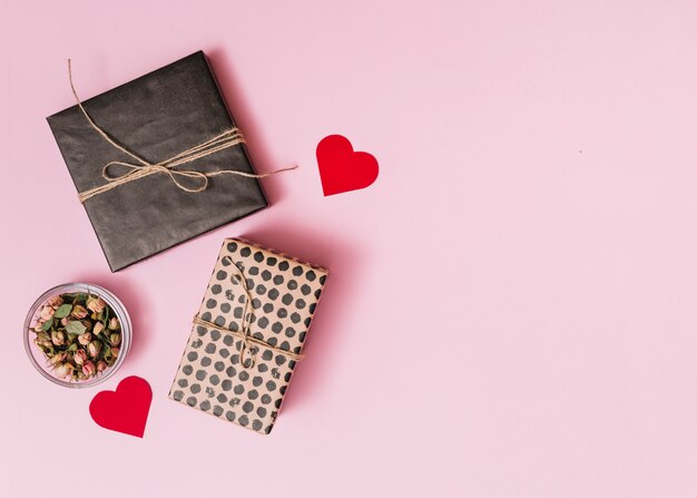 Composition of present boxes near ornament hearts and flowers in glass