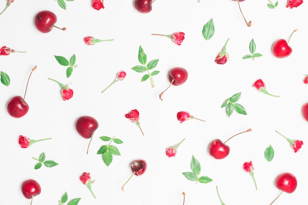 Composition of red flowers, cherries and green leaves