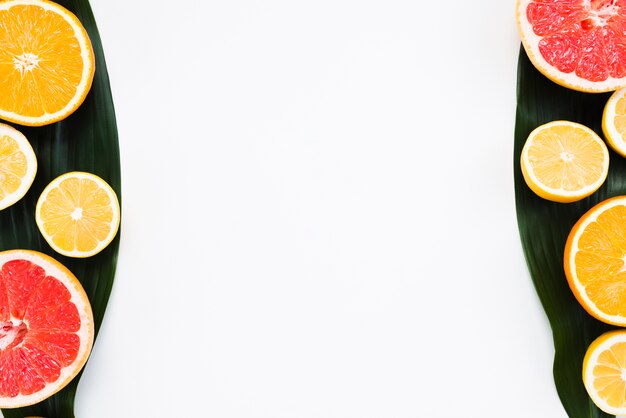 Composition of sliced exotic fruits on banana leaf on white background