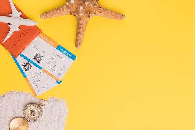 Composition of small plane passport tickets starfish and compass on towel