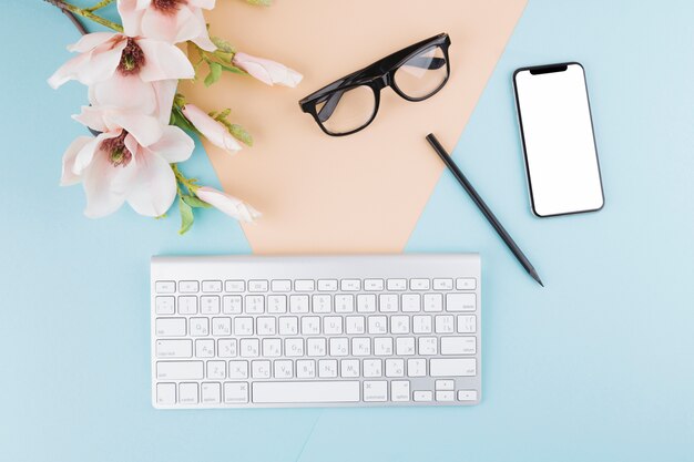 Composition of smartphone, keyboard, eyeglasses, flowers and pencil