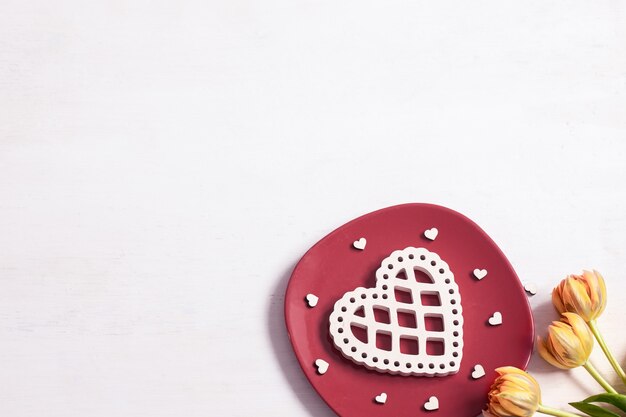 Composition for Valentine's Day with plate, flowers and decor element top view.
