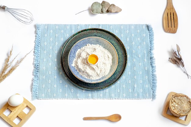 Composition with baking ingredients and kitchen accessories on a white table.