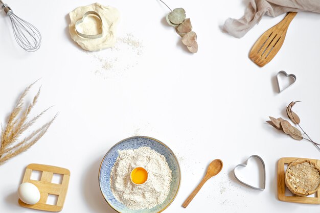 Composition with baking ingredients and kitchen accessories on a white table.