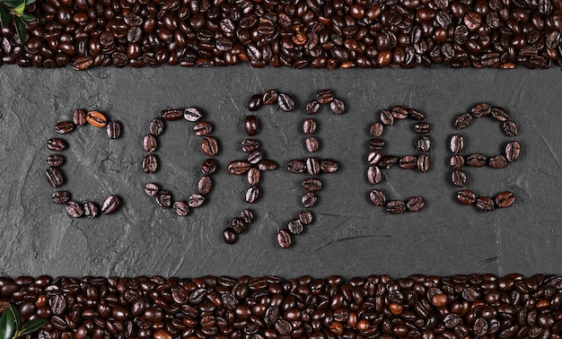 Free photo composition with coffee beans on the sides of a black background, the inscription of coffee beans on a black background in the middle of the frame. coffee roasted beans on black background