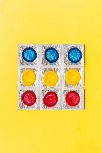 Composition with colorful condoms on yellow background. safe sex and contraceptive concept. flat lay, top view, copy space.