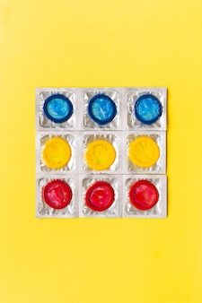 Composition with colorful condoms on yellow background. safe sex and contraceptive concept. flat lay, top view, copy space.