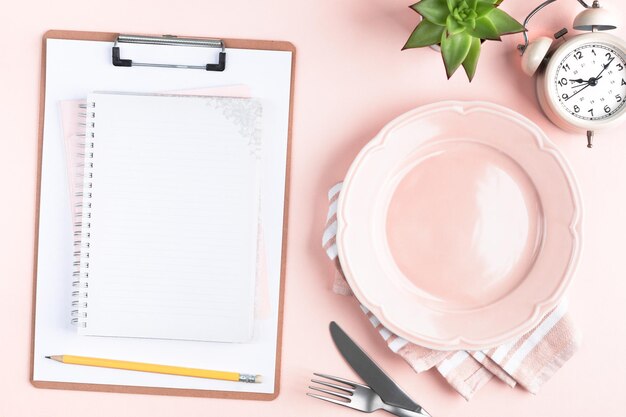 Composition with cutlery, measuring tape, blank paper notebook, spinach, apple, water and alarm clock on color background. Diet concept, copy space