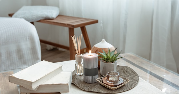 Composition with incense sticks, diffuser, candles and books on the table in the interior of the room.