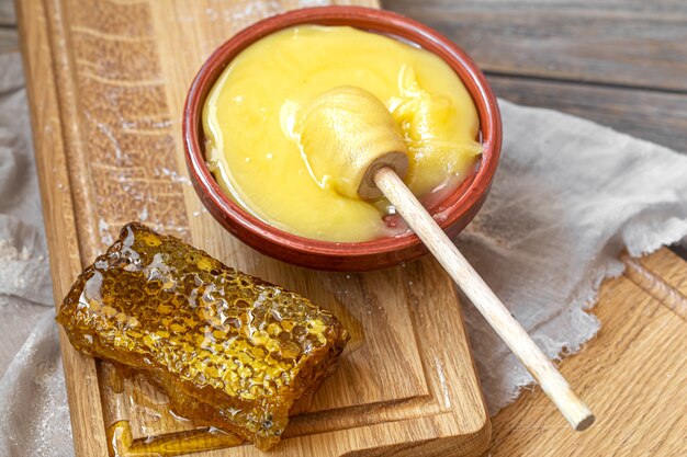 Composition with natural honey and honey dipper on wooden background close up.