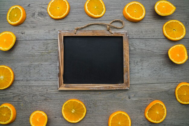 Composition with orange slices and blank blackboard