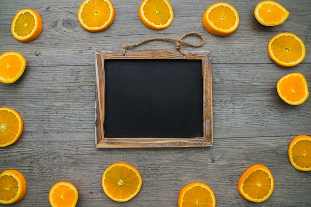 Composition with orange slices and blank blackboard