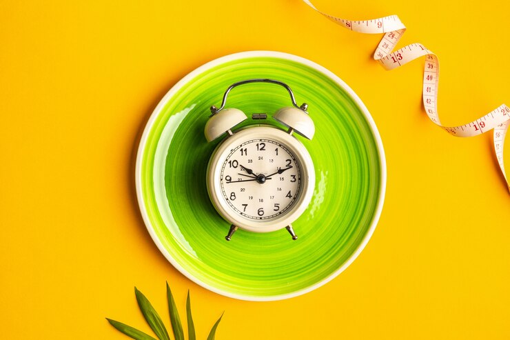 Composition with plate, alarm clock and measuring tape on a colored background. Diet concept and weight loss plan, copy space