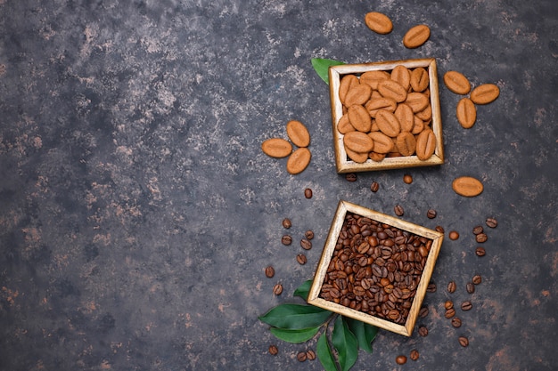 Композиция с жареными кофейными зернами и печеньем в форме кофейных зерен на темно-коричневой поверхности Бесплатные Фотографии