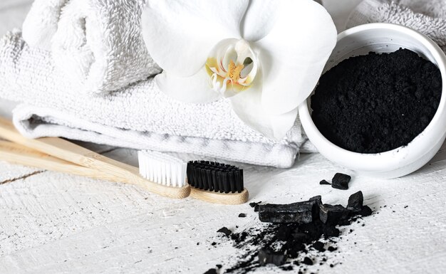 Composition with a wooden natural toothbrushes, black teeth whitening powder and orchid flower copy space.