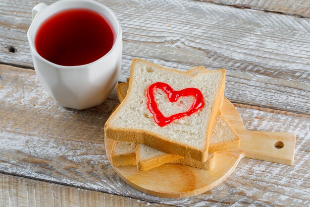 Compote in a cup with jam on toast bread high angle view on wooden and cutting board