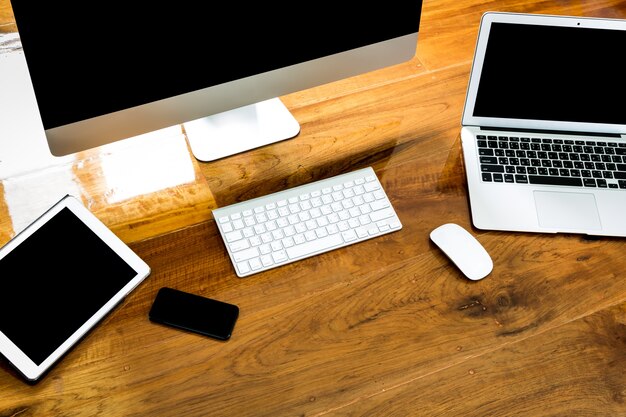 Computer, laptop and tablet view from above on a wooden table