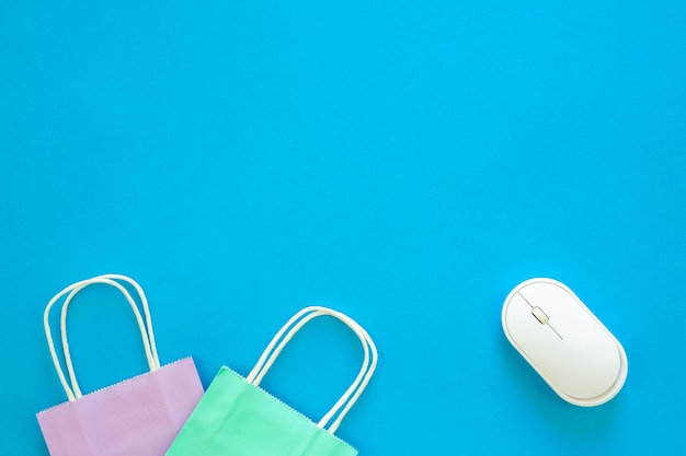 Computer mouse and paper bags on a blue background top view