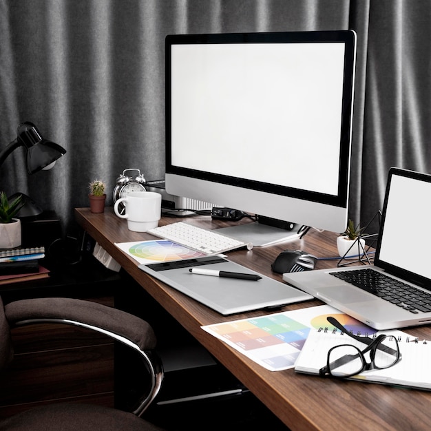 Computer screen and laptop on office workspace with color palettes