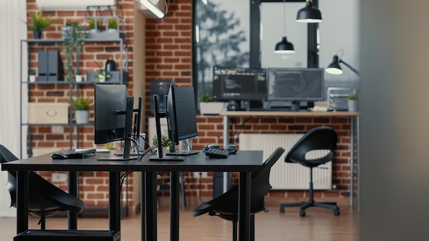 Computer screens on desk in empty data room and computers in background running programming code data algorithms. Neural network servers cloud computing in software it agency office.