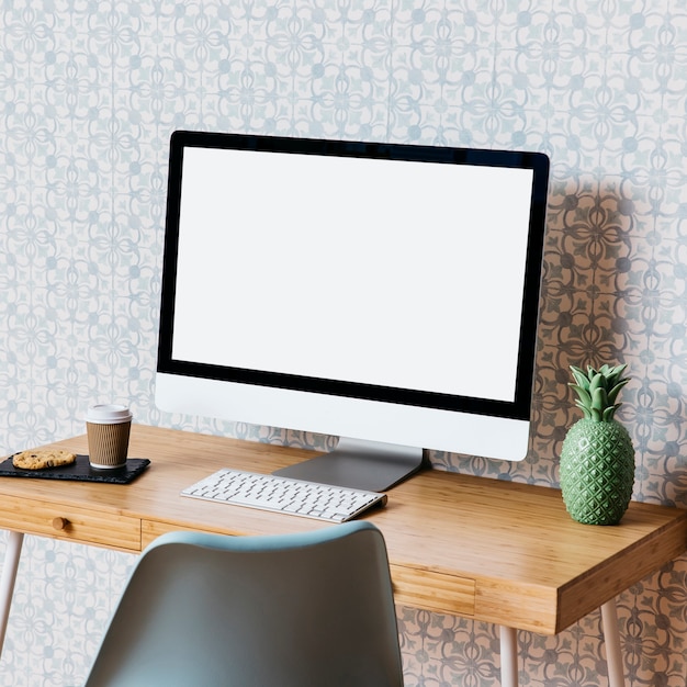 Computer with cookies and disposal cup on wooden desk