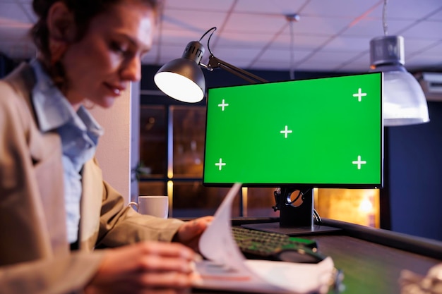 Free photo computer with green screen mock up chroma key with isolated display standing on desk in startup office. businesswoman analyzing marketing statistics, working at investment strategy to increase profit