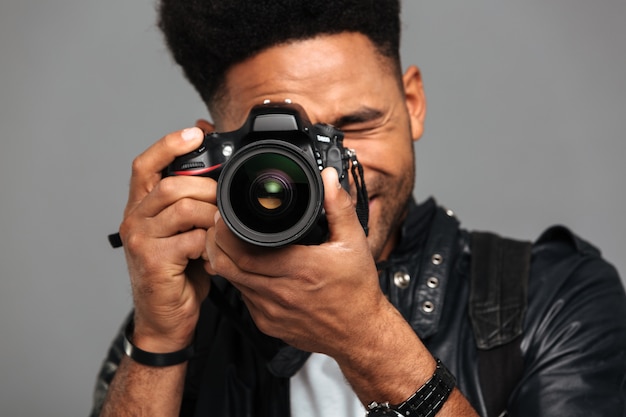 concentrated afro american man taking photo on digital camera