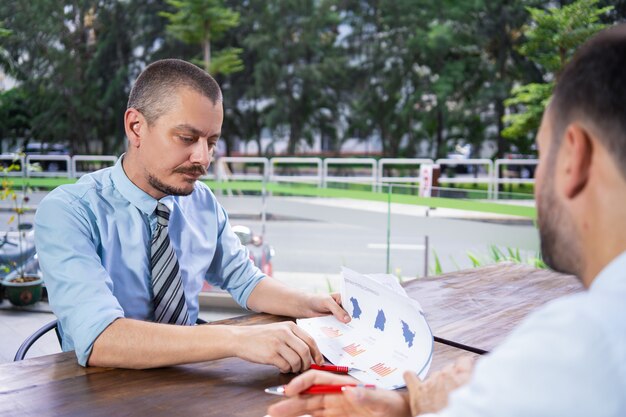 Concentrated businessman showing report to colleague